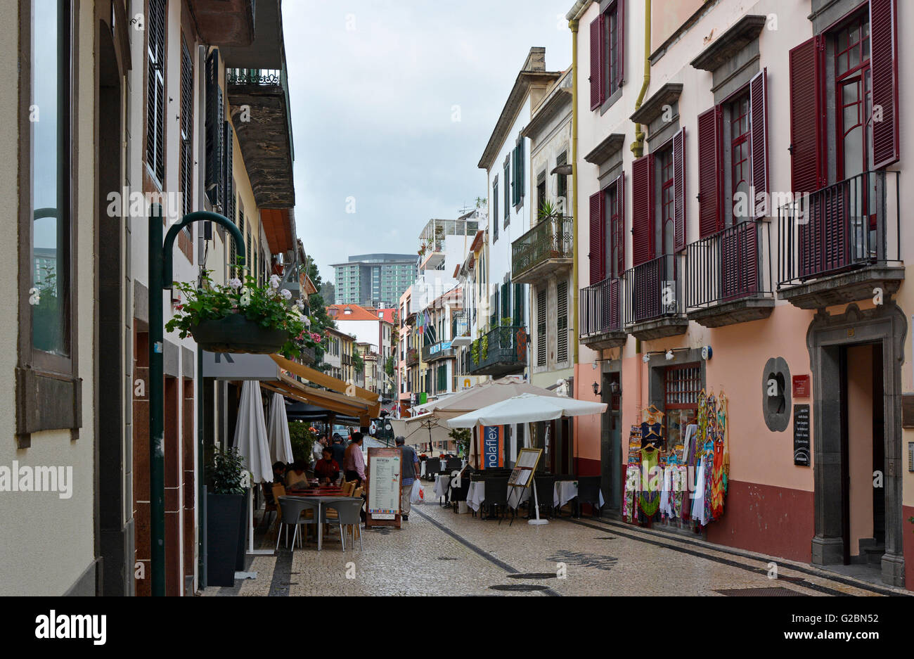 Street with shops and cafes in centre of Funchal, Madeira, Portugal. With people sitting outside cafe. Stock Photo