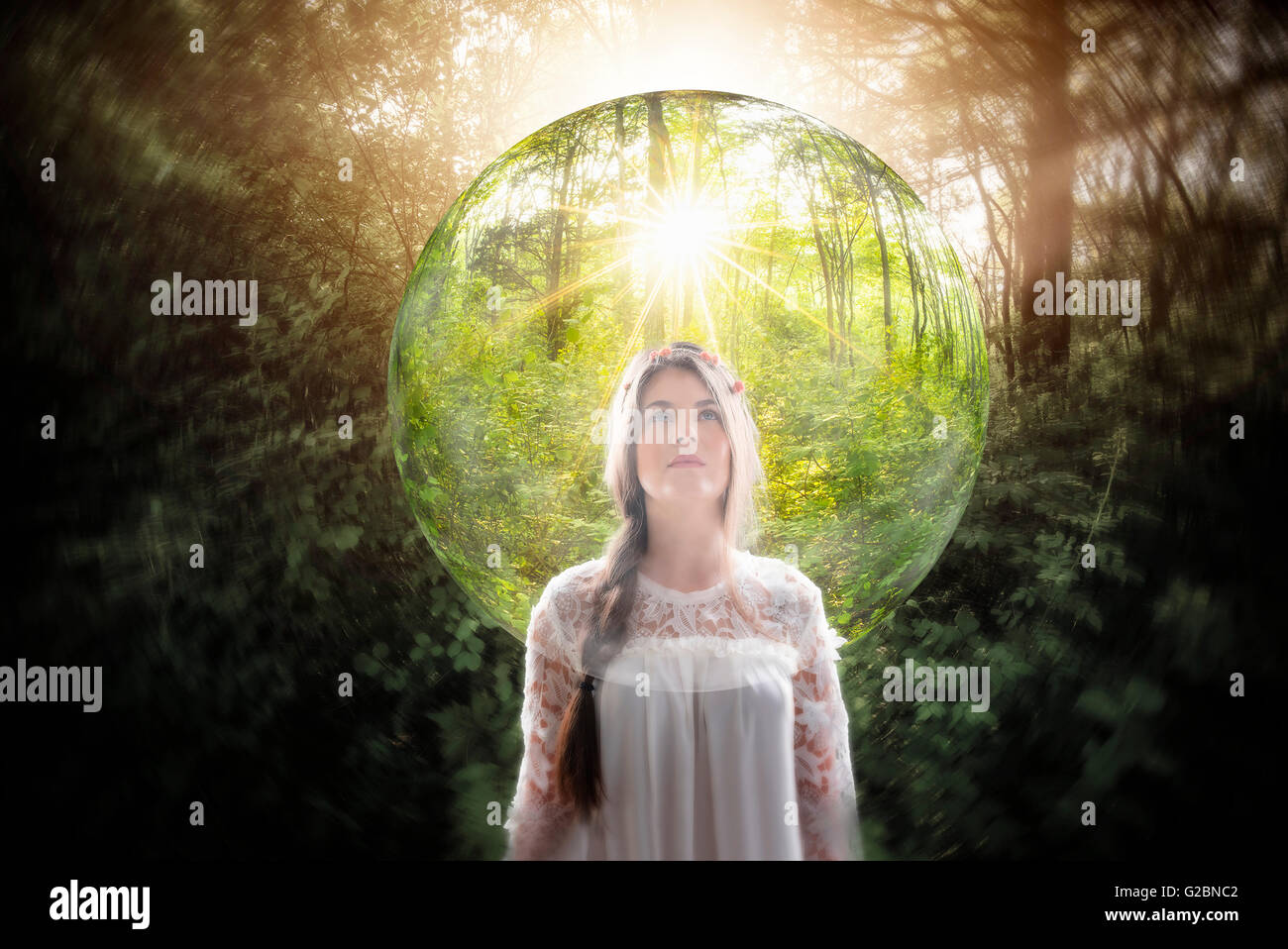 Young woman in forest looking at transparent sphere Stock Photo