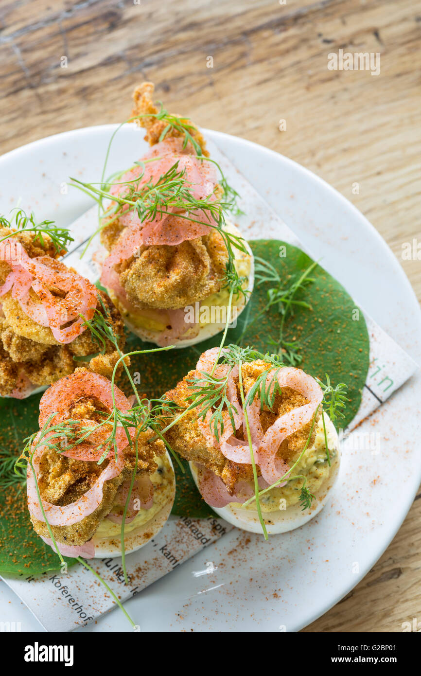 Deviled eggs with cornmeal fried oysters and pickled red onion Stock