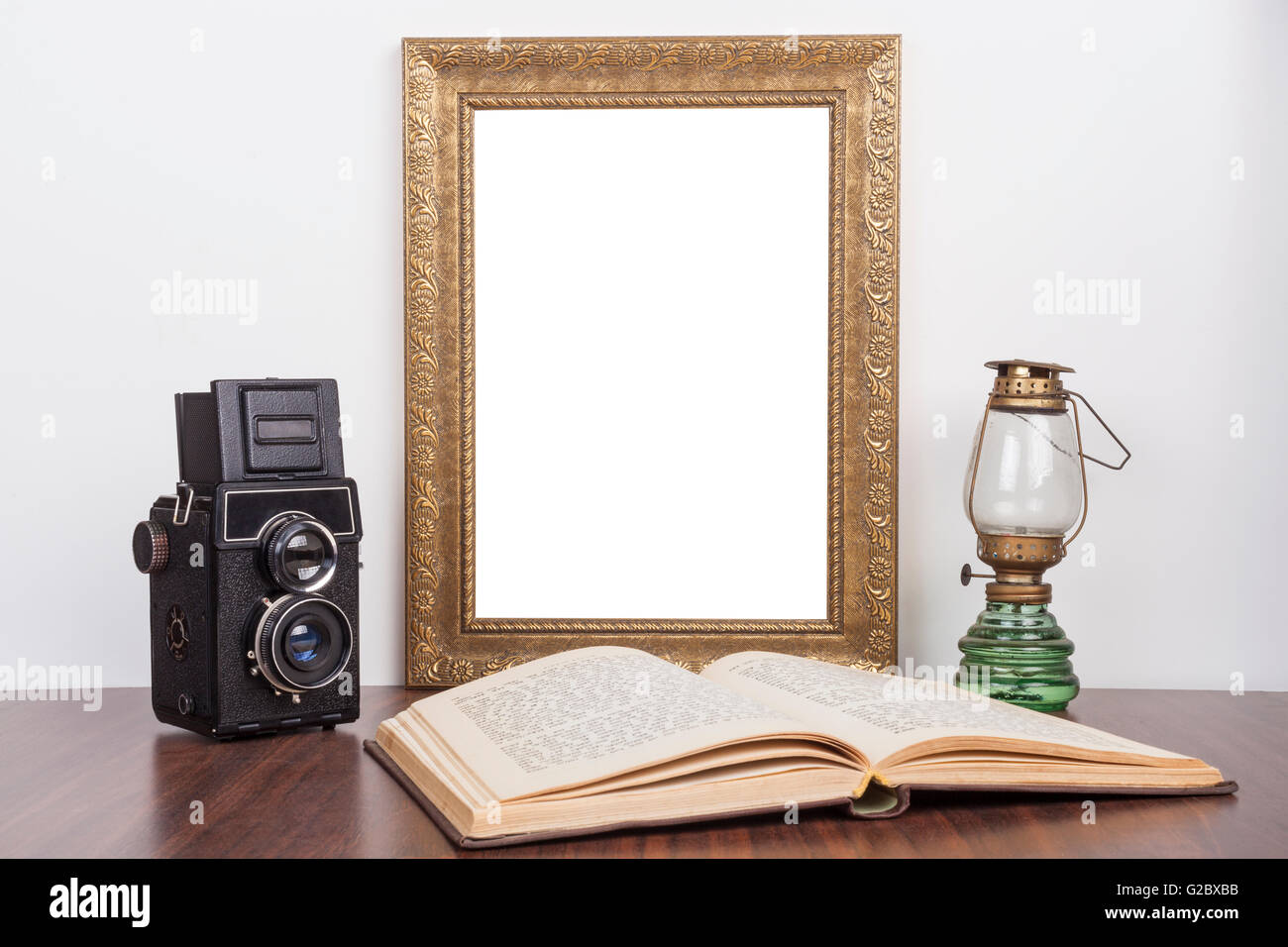 Old Gold portrait frame with old camera and open book with lamp Stock Photo