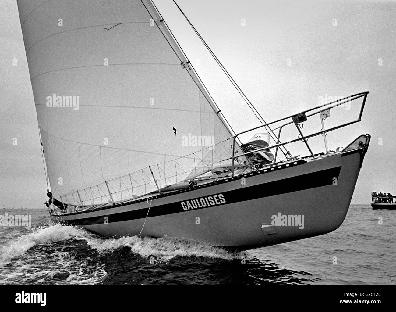AJAX NEWS PHOTOS.1976. PLYMOUTH, ENGLAND. - OSTAR - SWISS SKIPPER PIERRE FEHLMANN PEERS AROUND THE HUGE GENOA OF HIS YACHT GAULOISES AT THE START OF THE RACE OFF PLYMOUTH. HE RETIRED. PHOTO:JONATHAN EASTLAND/AJAX. REF:2760506/21 Stock Photo