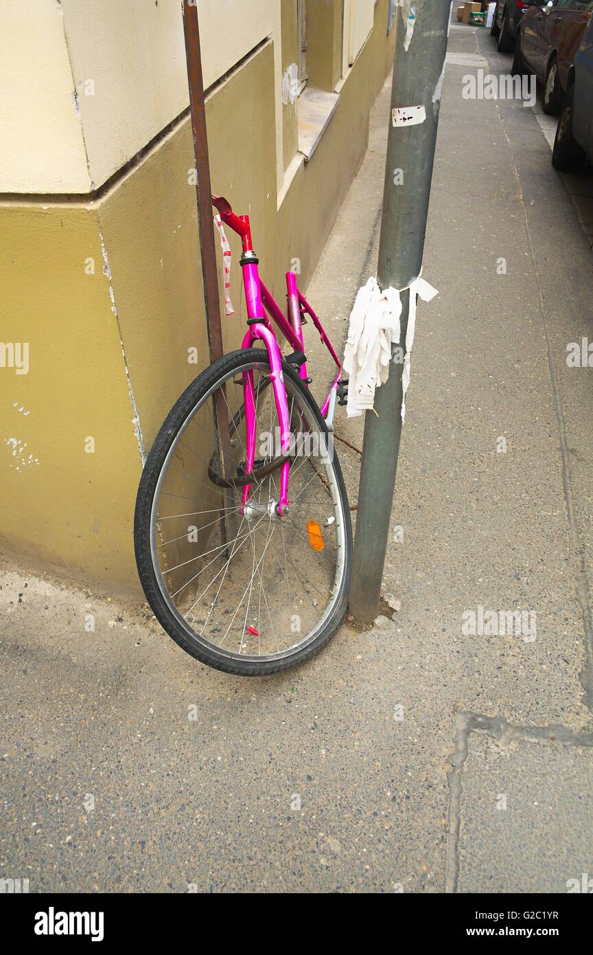 Broken and stolen beloved pink bicycle on the street. It looks like a corrupt petty street crime and violence. Stock Photo
