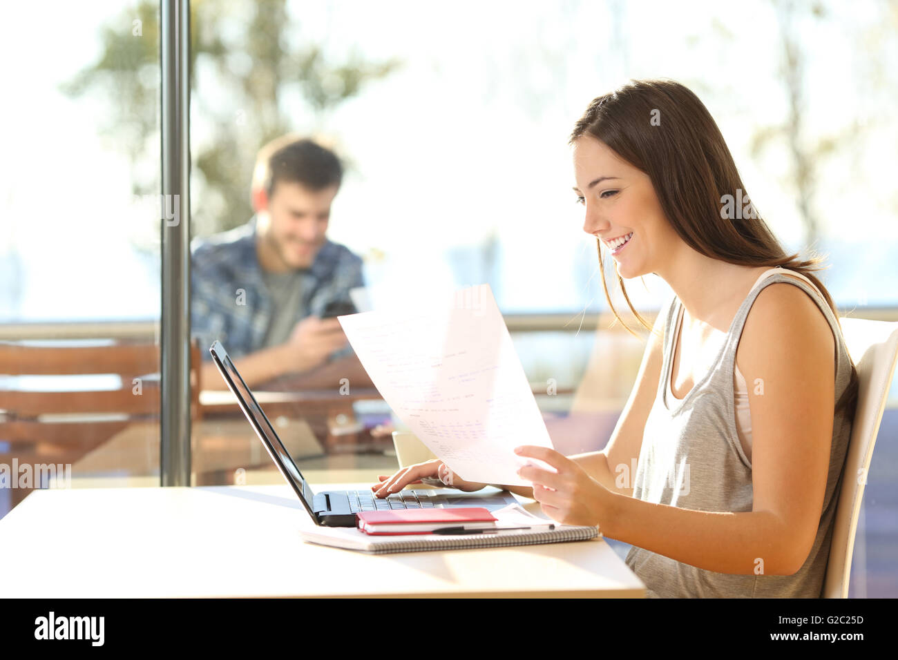 Side view of a beautiful student or freelance studying on line and learning reading notes in a restaurant Stock Photo