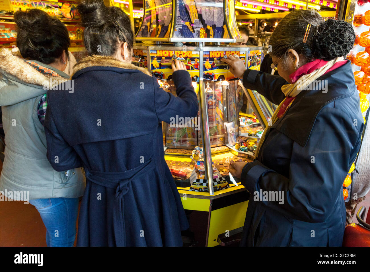 Women playing a slot machine in an amusement arcade at Goose Fair, Nottingham, England, UK Stock Photo