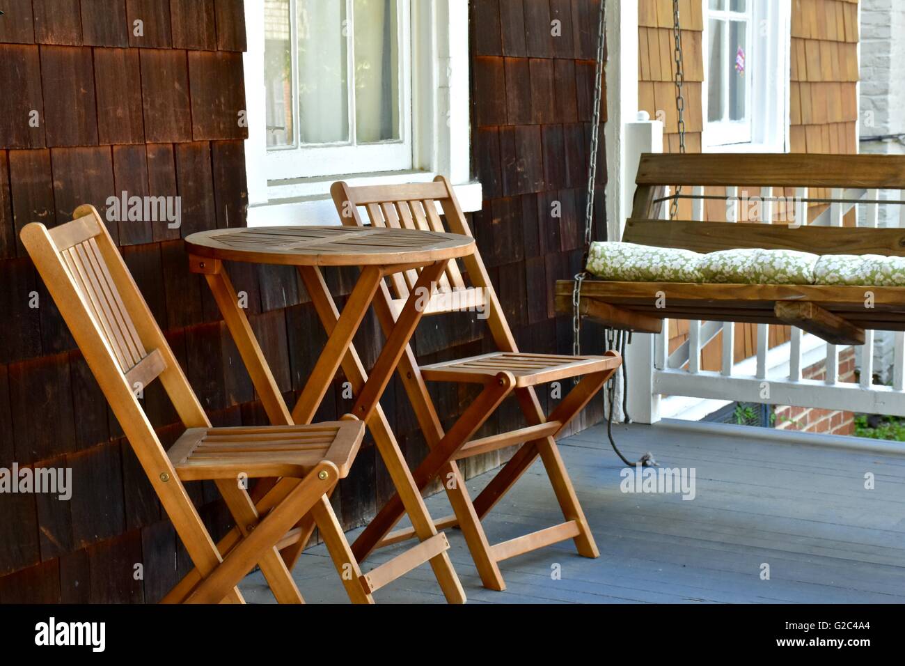 Front porch with wood chairs, table, and a swing Stock Photo