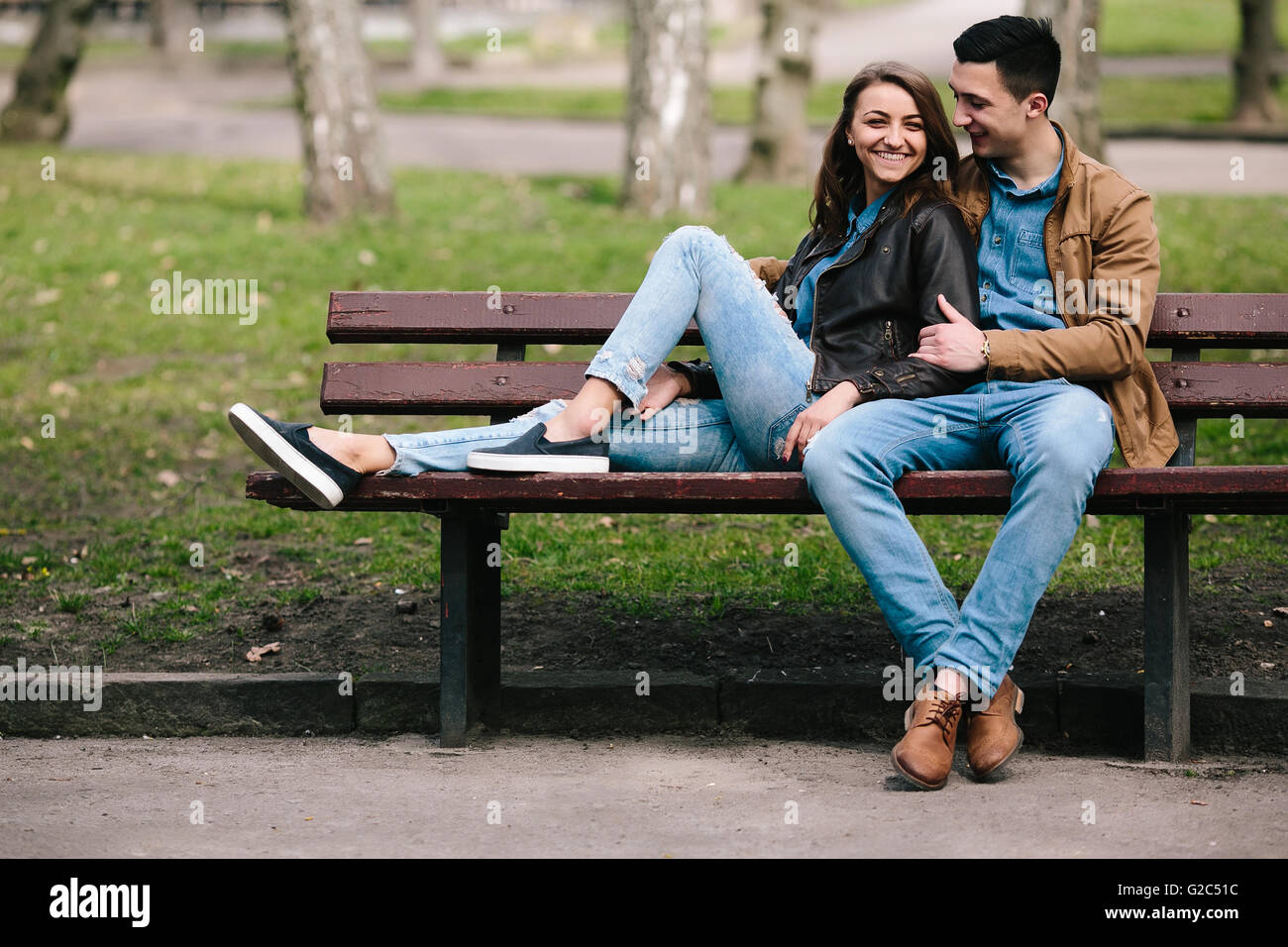 beautiful young couple relaxing on a bench in the park Stock Photo - Alamy