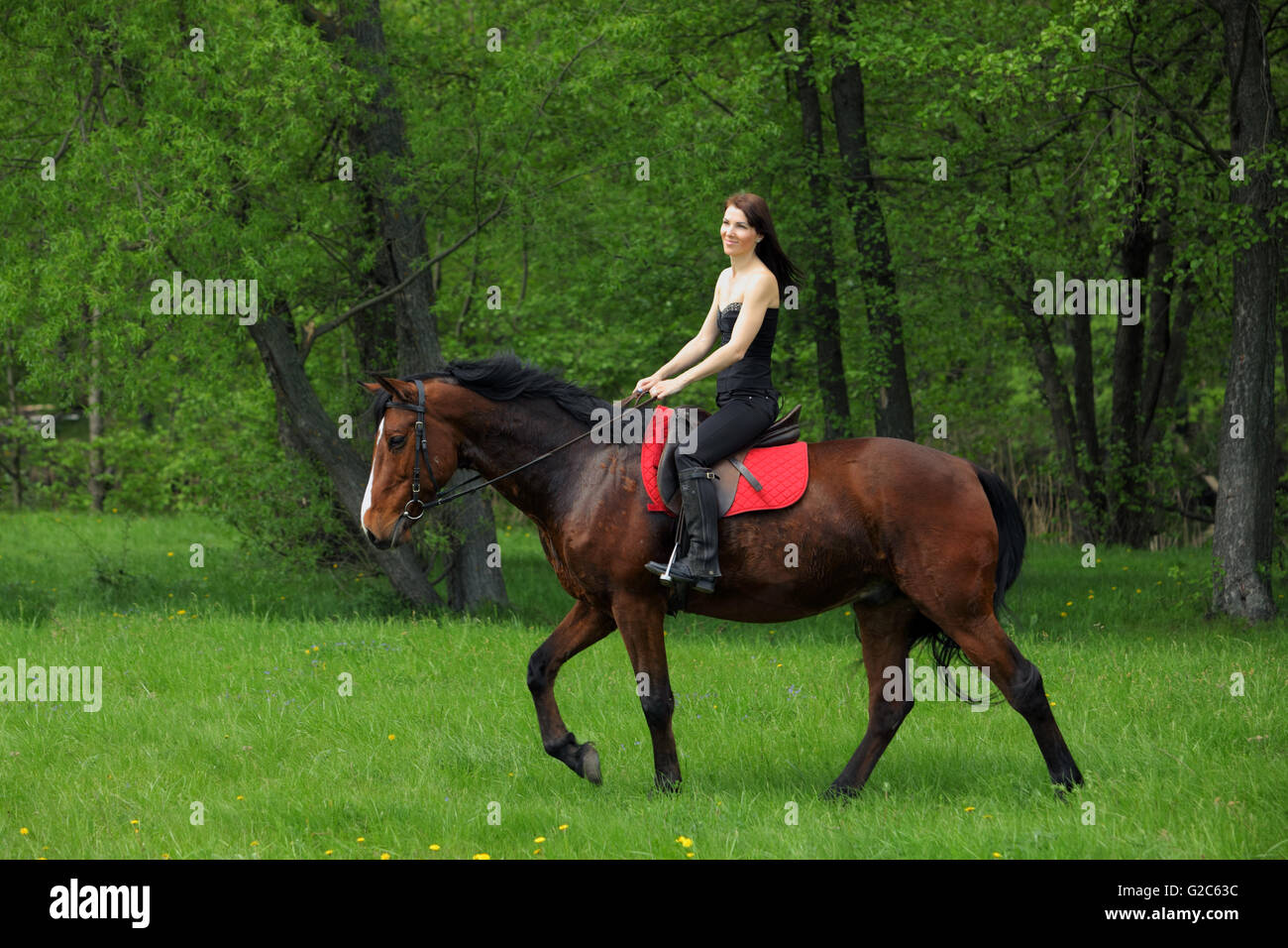 Cheerful young woman and her galloping horse Stock Photo