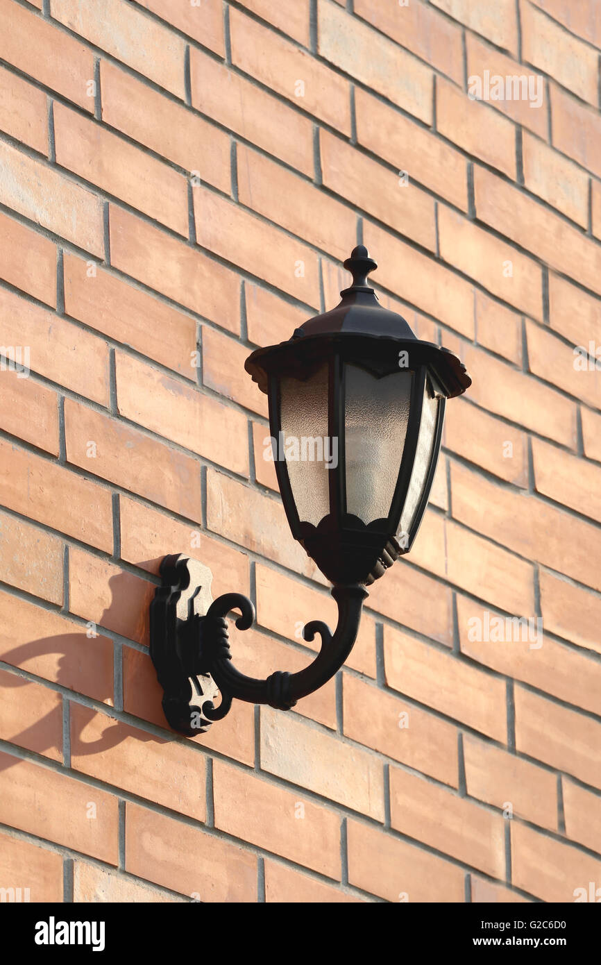 Black Lantern mounted on brown brick wall in exterior. Stock Photo
