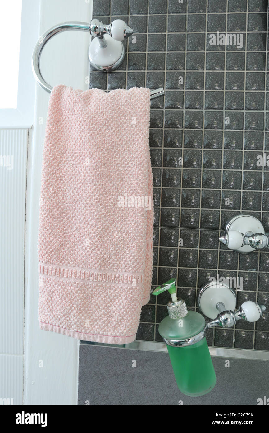 Bottle of liquid soap and pink towels have hanging on a clothesline of bathroom interior in the house. Stock Photo