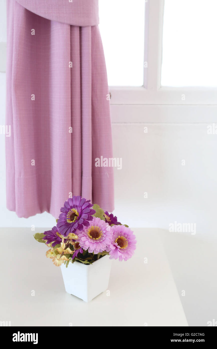 Vintage pink artificial flowers on a table in the white bedroom