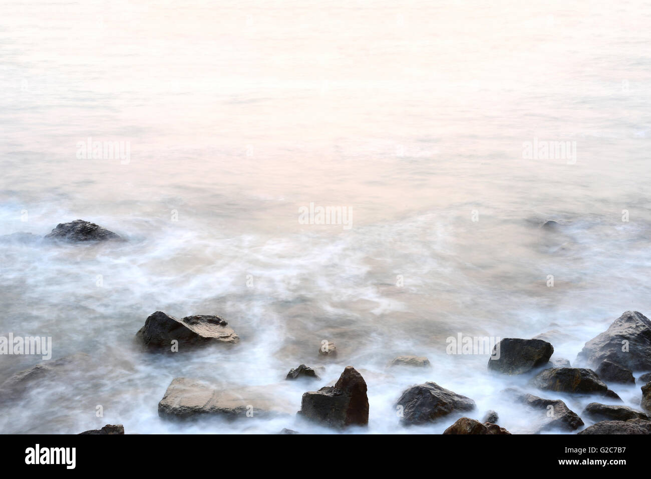 Sea mist softness of the tides and sunset at evening with rocks in foreground,viewpoint in Chanthaburi Thailand. Stock Photo