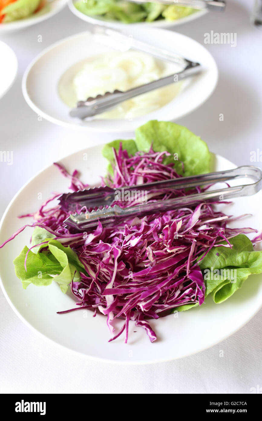 sliced purple cabbage in a white dish of vegetable salad on food table. Stock Photo
