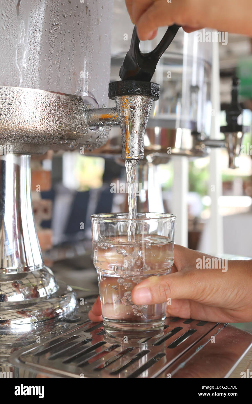 woman's hands were pressing cool water into drink glass in a restaurant. Stock Photo