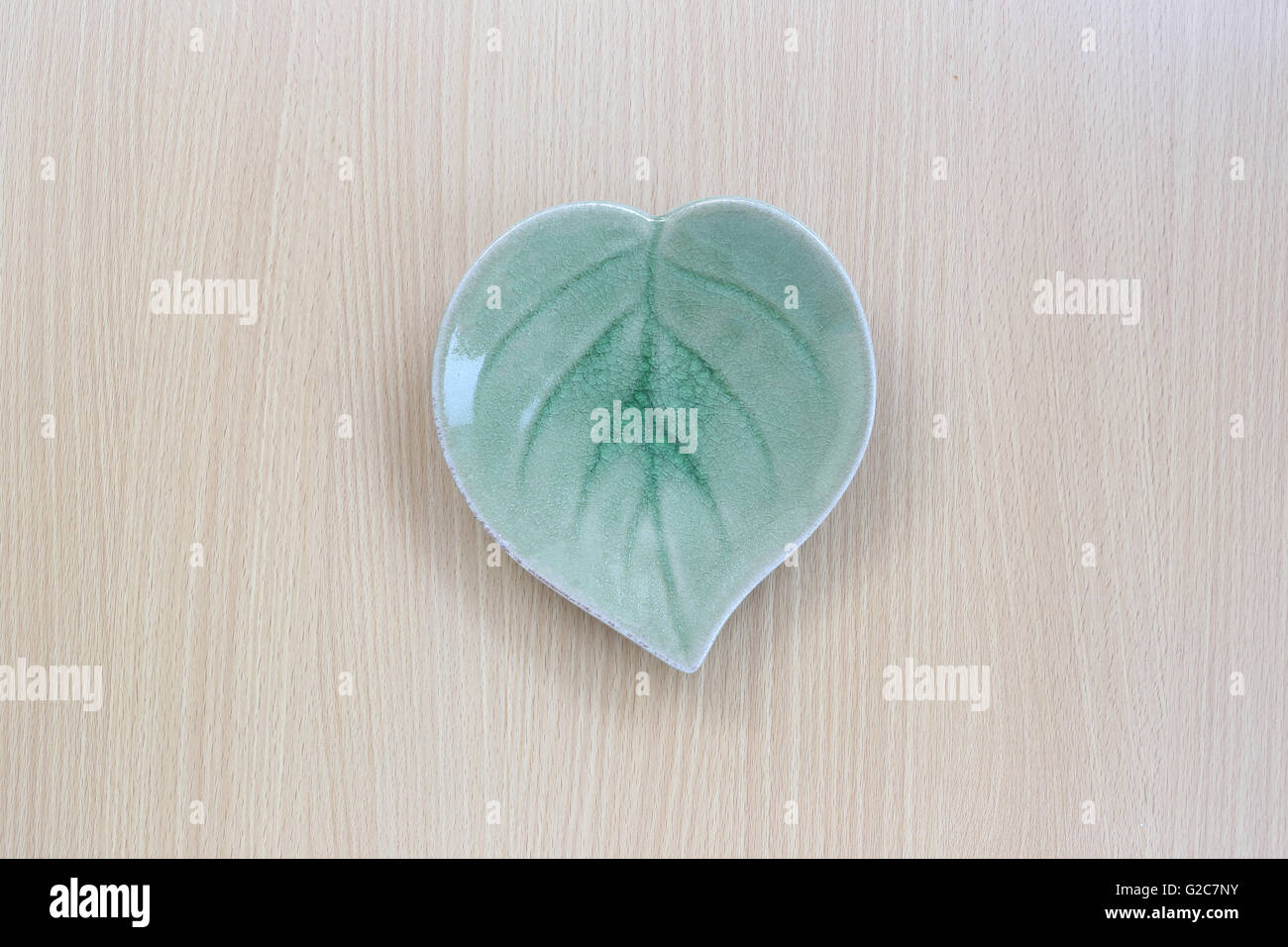Green leaf shape dish in top view on wood background for design concept food. Stock Photo