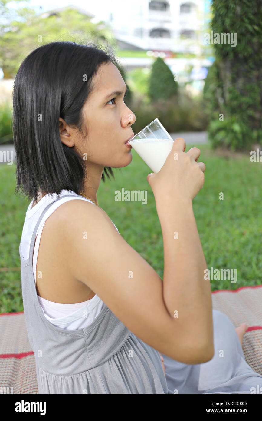 Asia pregnant mom was drinking milk in the garden for good health. Stock Photo