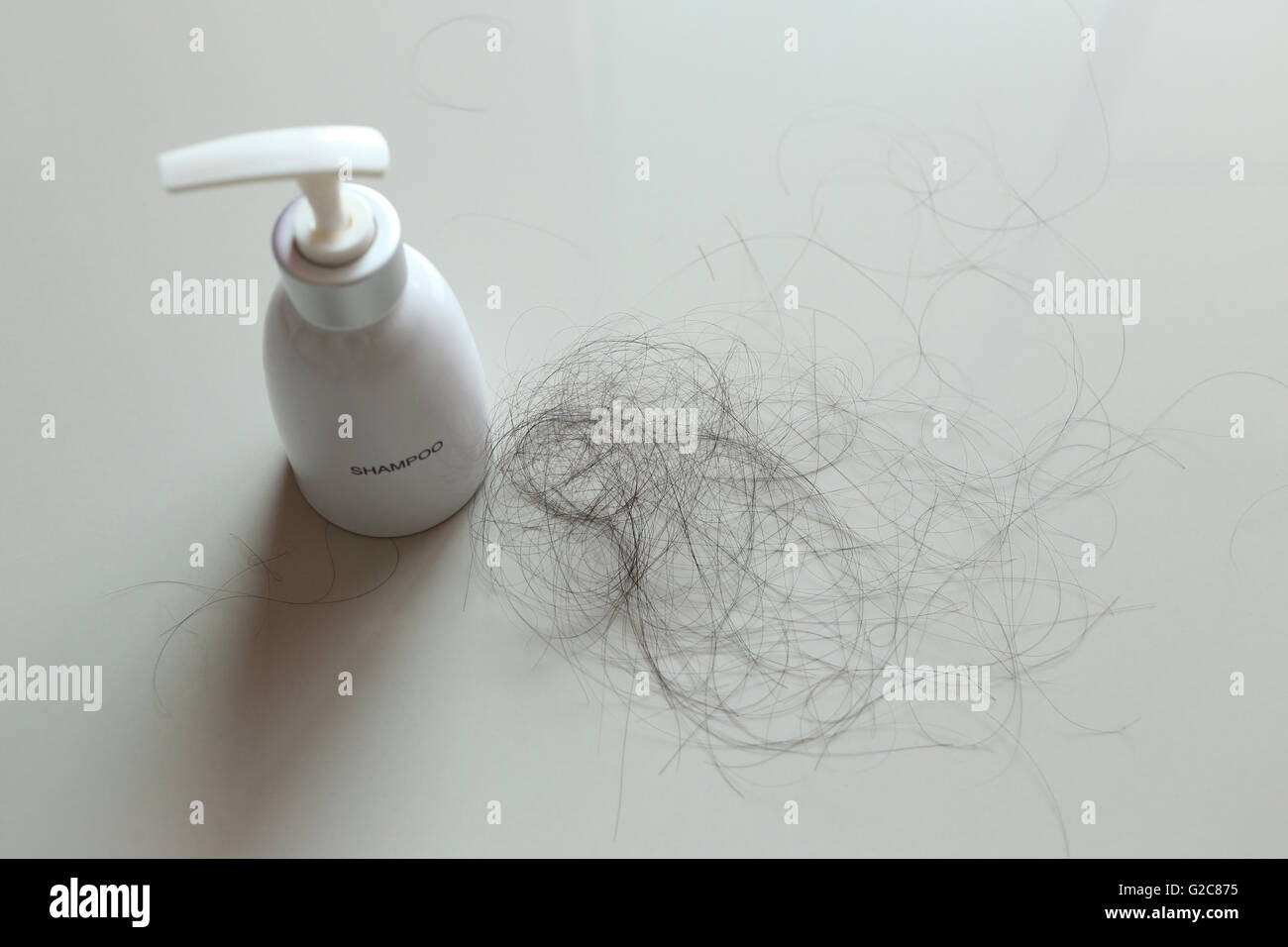 White Bottle of shampoo and hair loss on white fabric in concept healthcare. Stock Photo
