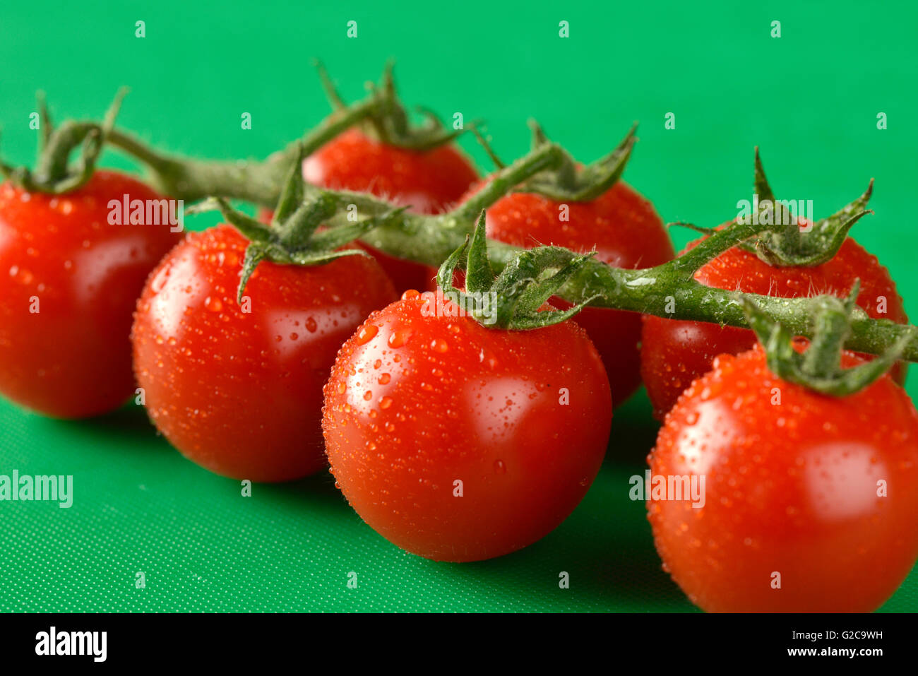 Tomatoes on the vine shown on a green chopping board, the correct ...