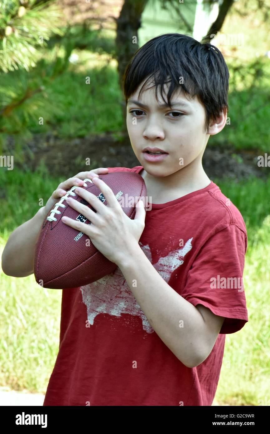 A young boy playing football in a field Stock Photo