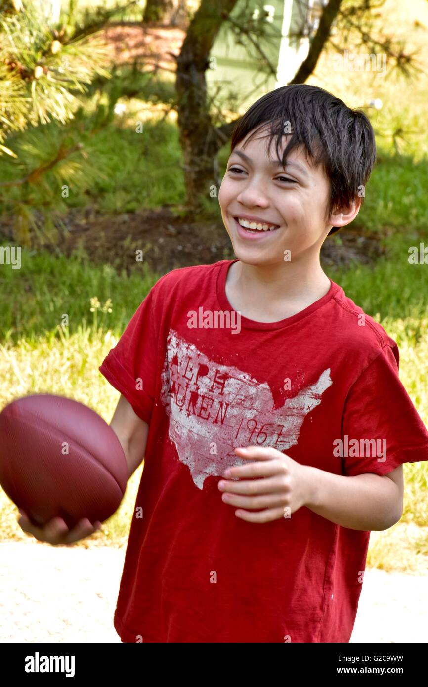 A young boy playing football in a field Stock Photo