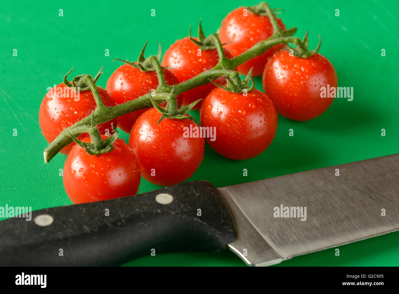 Tomatoes on the vine shown on a green chopping board, the correct ...