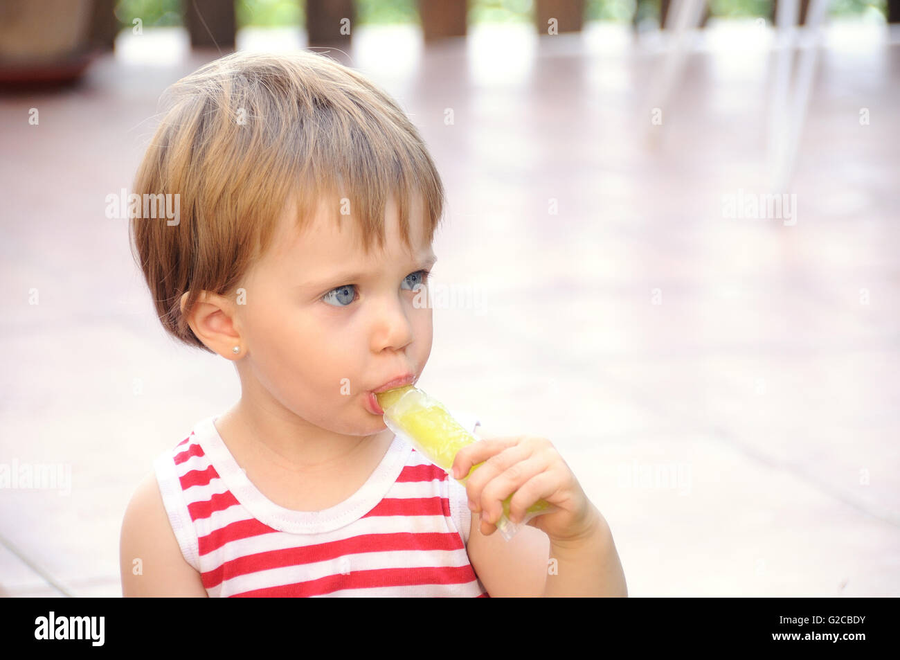 blue eyed girl sucking a lemon ice cream on a terrace Stock Photo