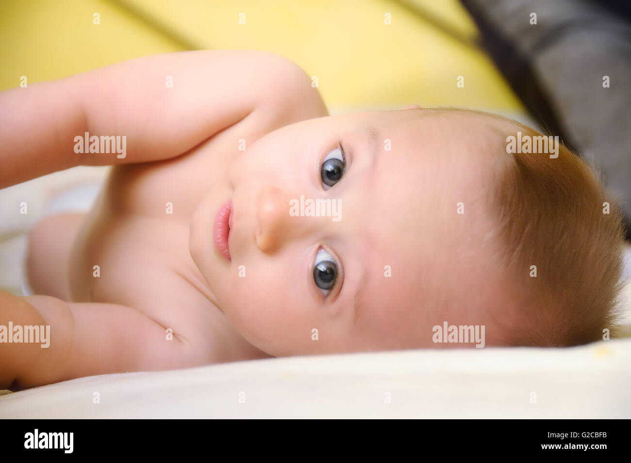 tender baby lying in bed yellow background Stock Photo