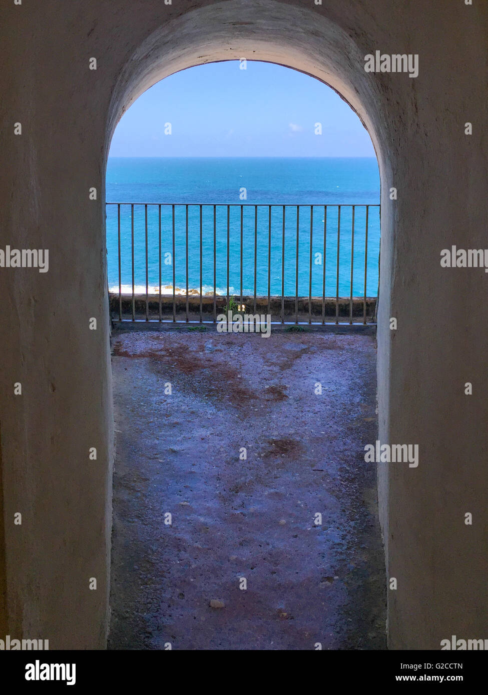 an old cement archway opening up to the sea and sky beyond Stock Photo