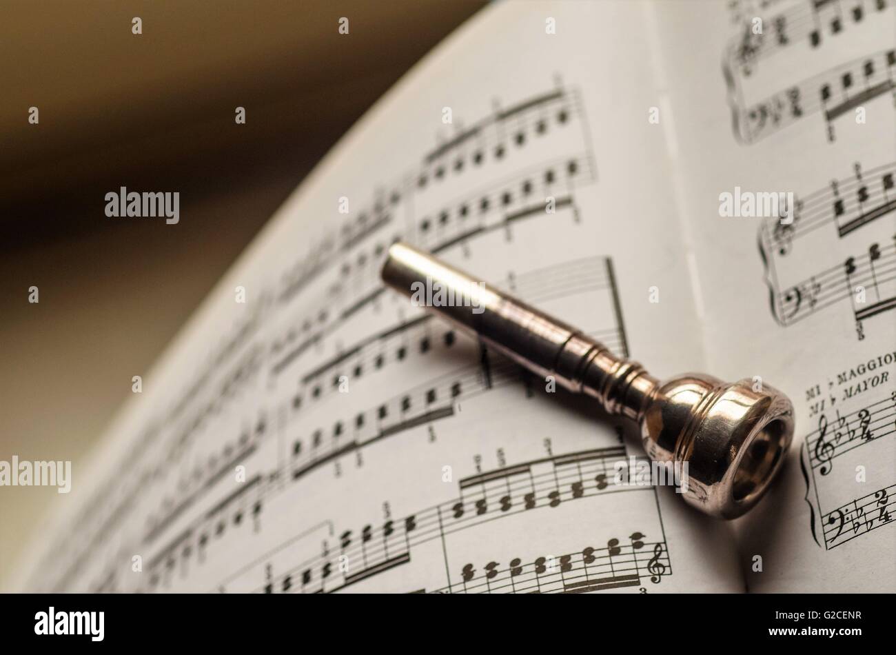 trumpet mouthpiece posed on a book of music sheets Stock Photo