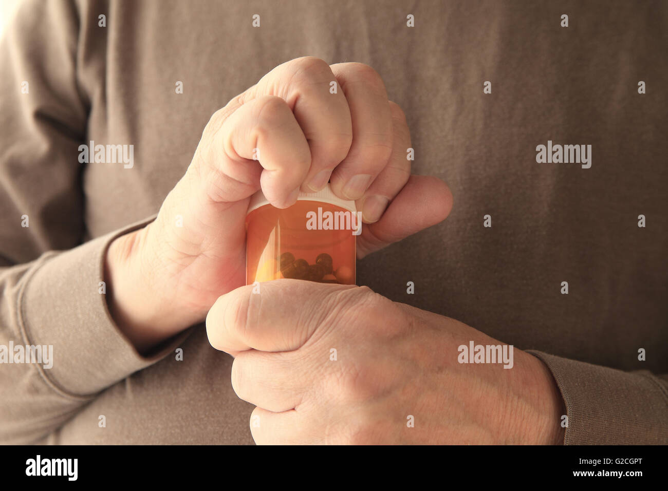 Older man struggles to get a container of capsules open. Stock Photo