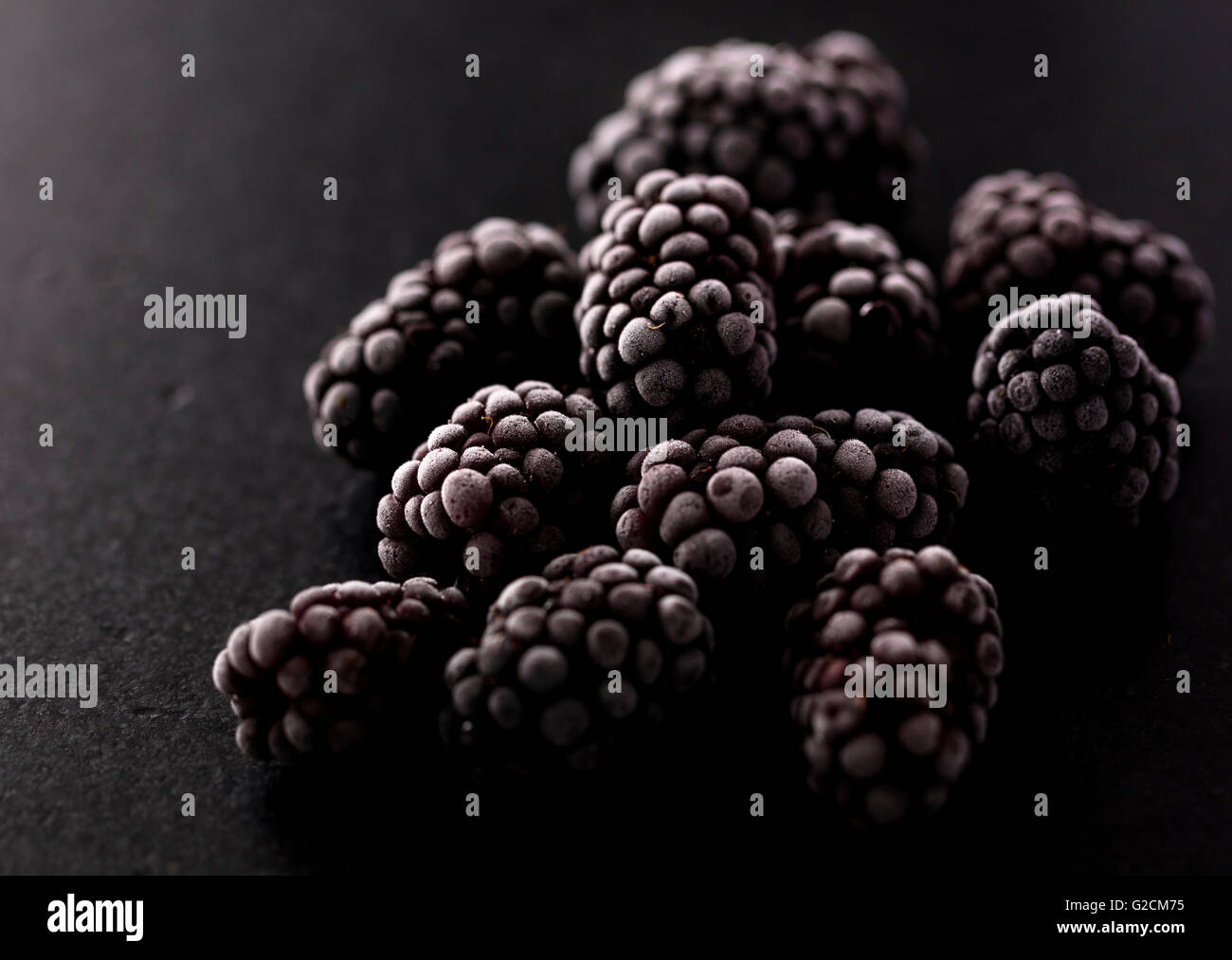blackberries frozen on a black stone, macro photo showing a beautiful ice texture Stock Photo