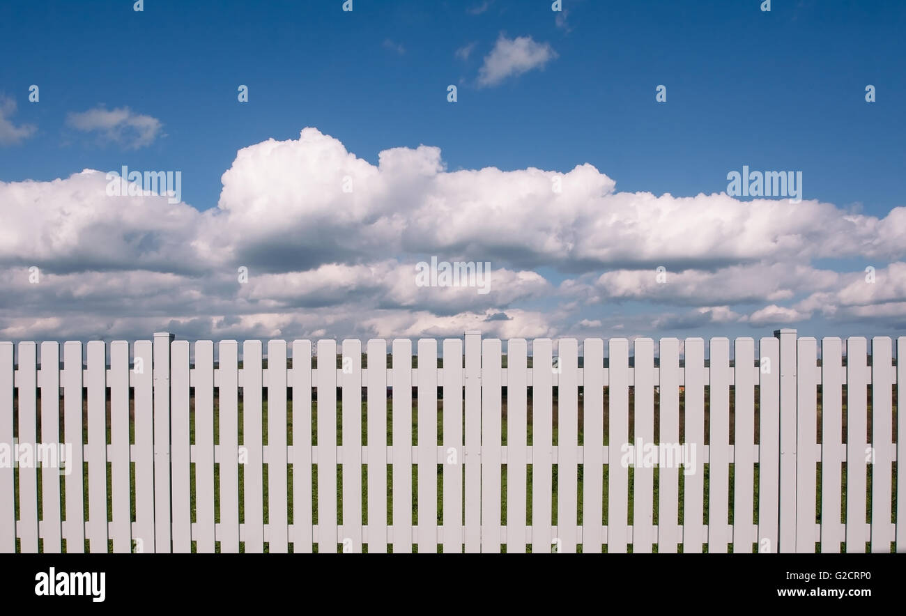Horizontal front view of a white wooden fence on front of a blue sky