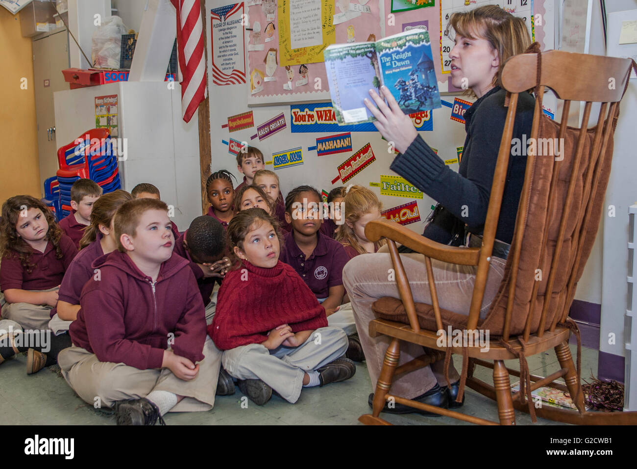 Teacher reading to students in the classroom Stock Photo - Alamy