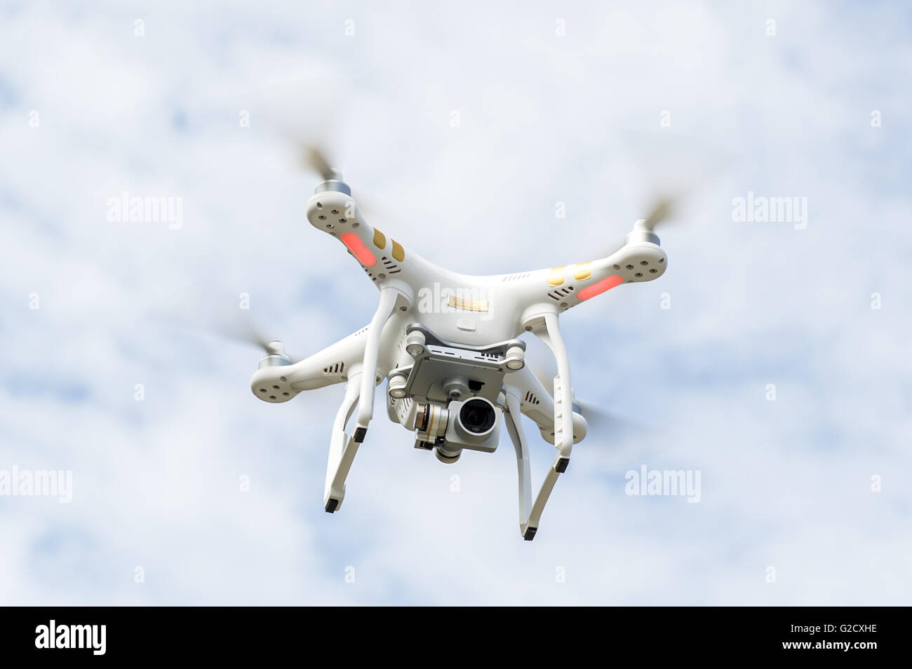 A DJI Phantom 3 Professional drone with camera hovers in the sky. Stock Photo