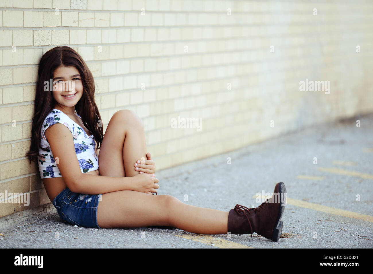 young girl leaning on brick wall Stock Photo