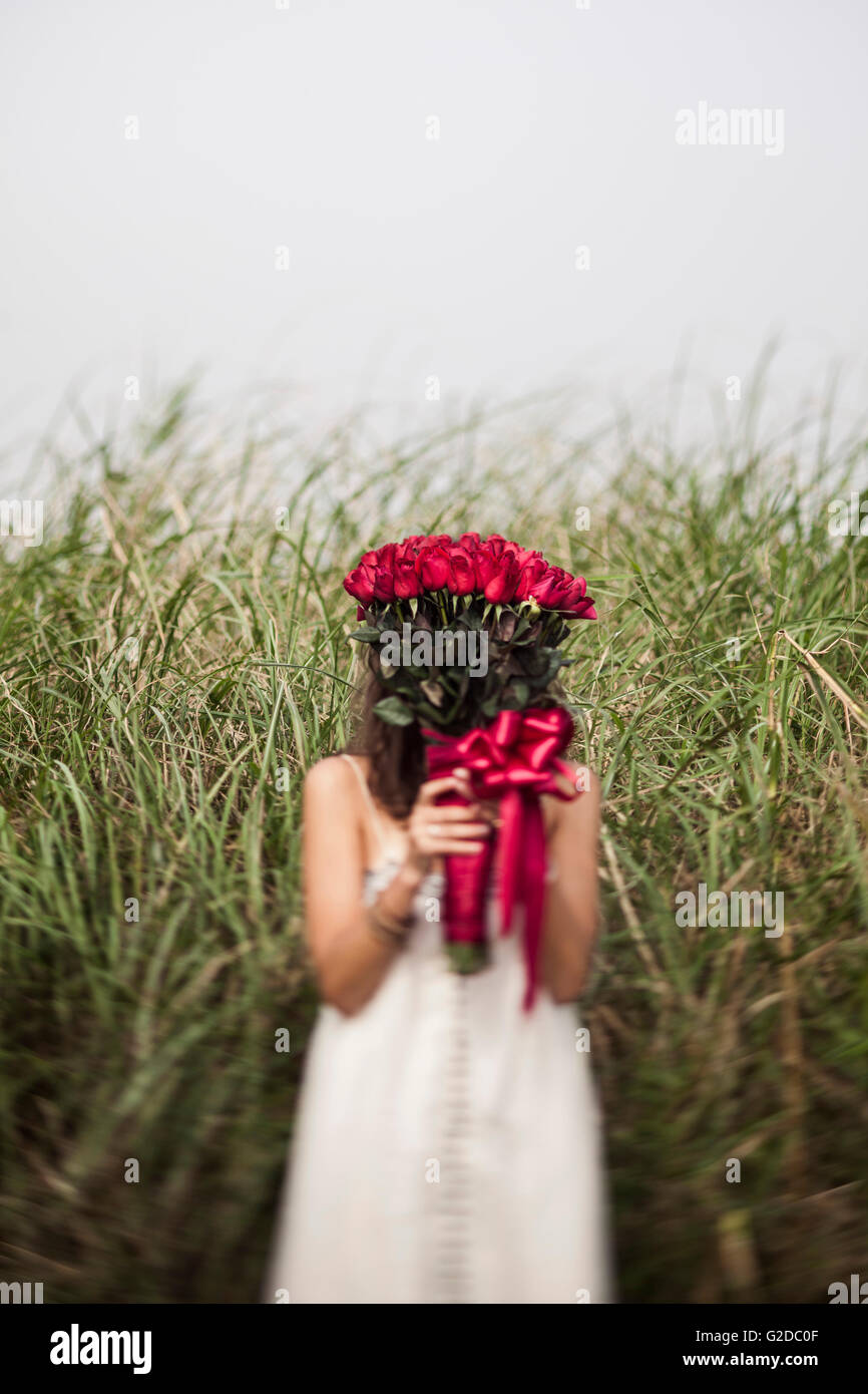 Young Woman Holding Bouquet of Red Roses in Front of Face in Grassy ...