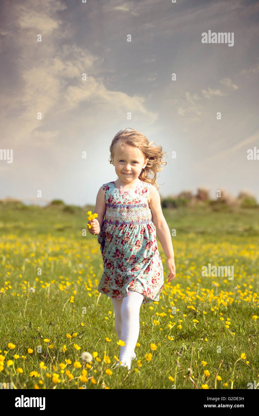 a 3 year old girl running through a flower meadow Stock Photo