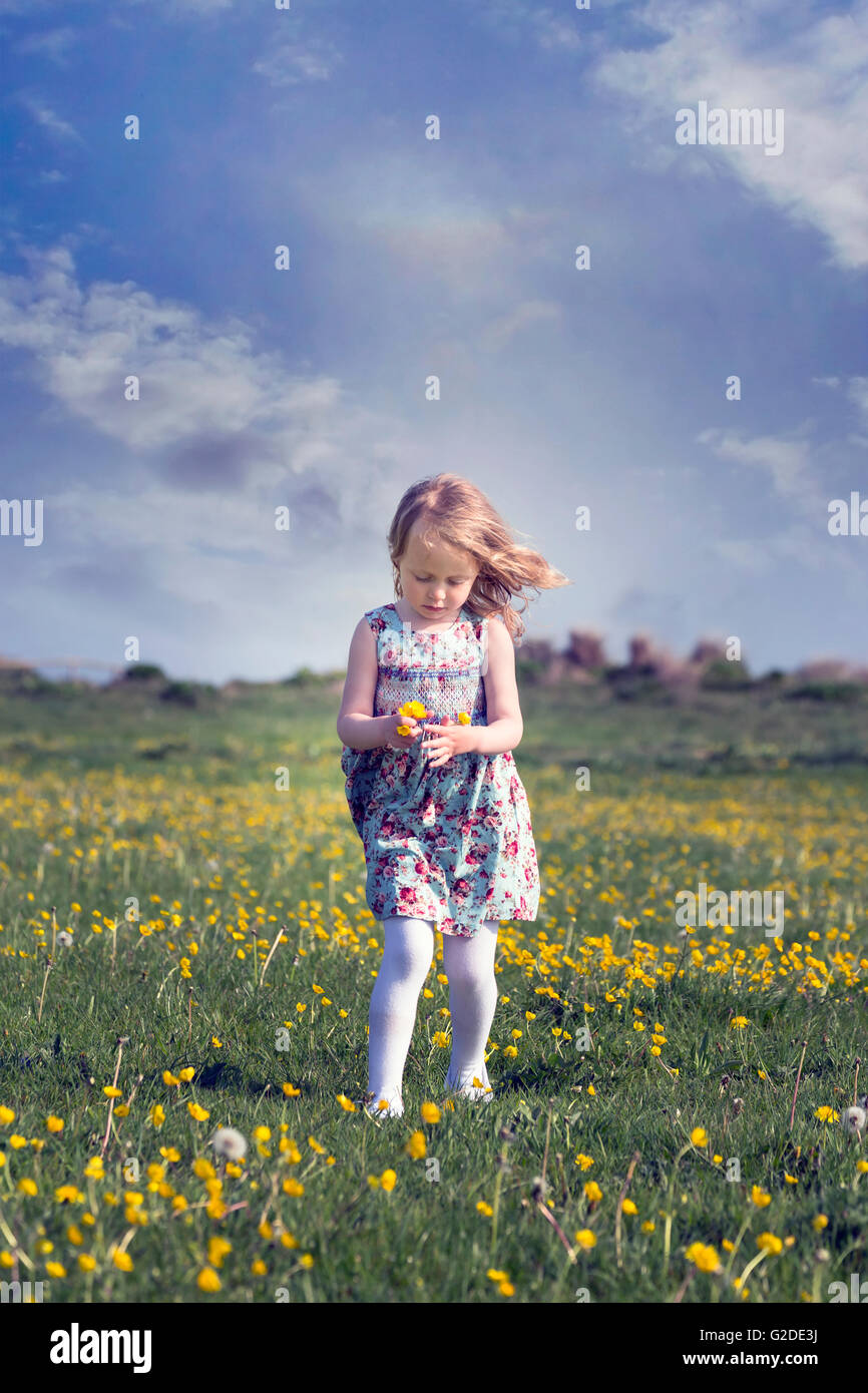 a 3 year old girl running through a flower meadow Stock Photo