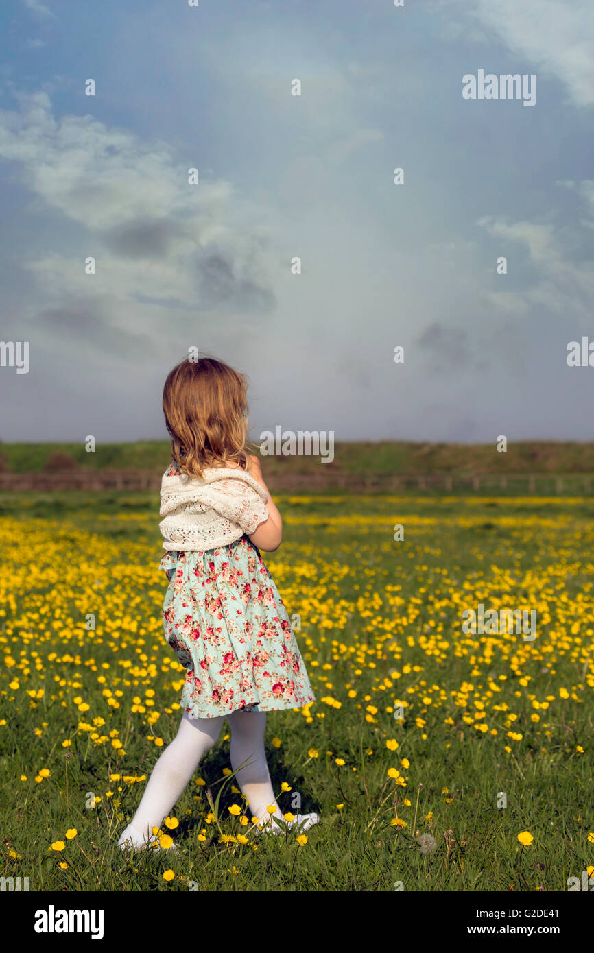 a 3 year old girl is walking on a flower meadow Stock Photo