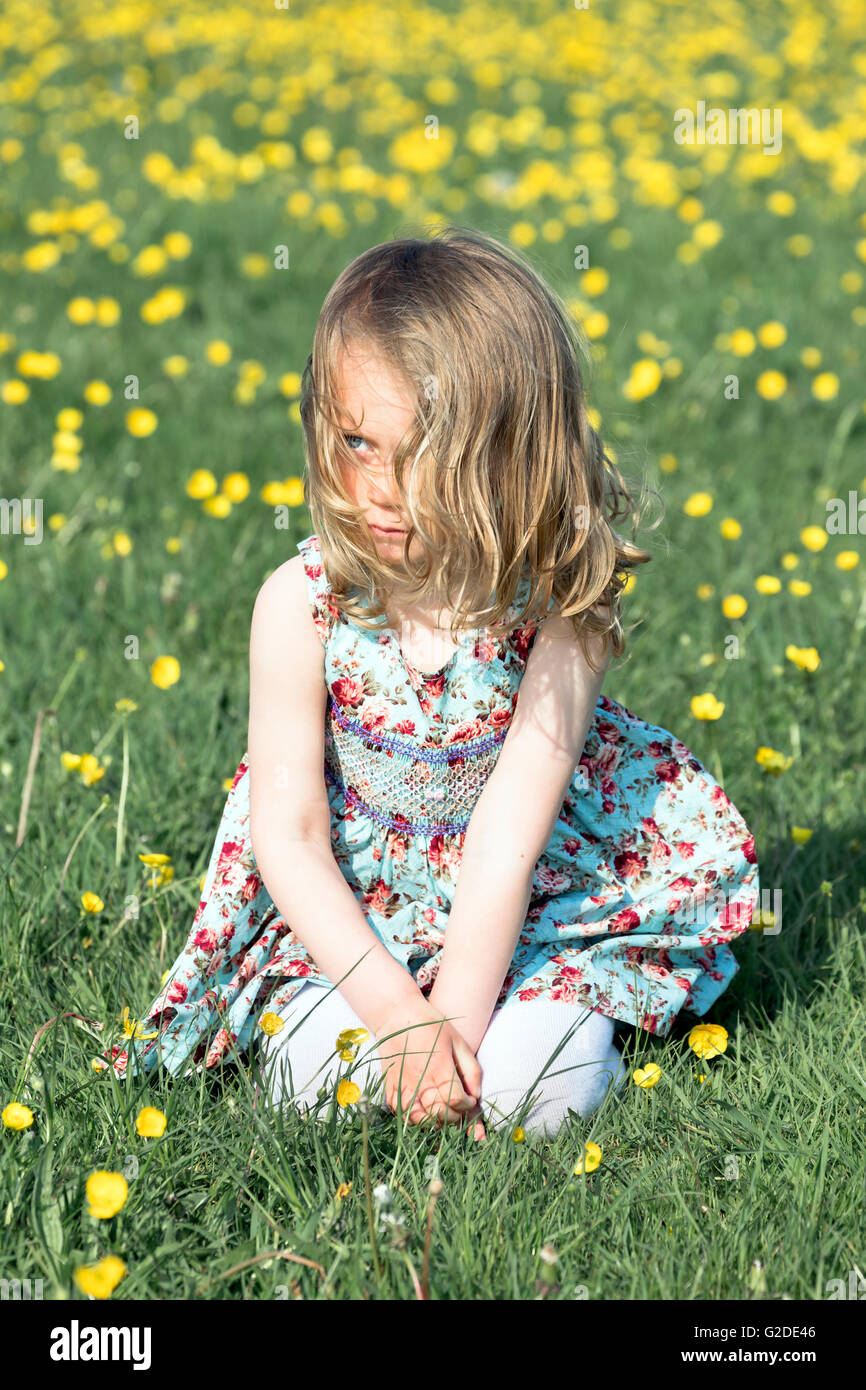 a 3 year old girl is sitting on a flower meadow Stock Photo