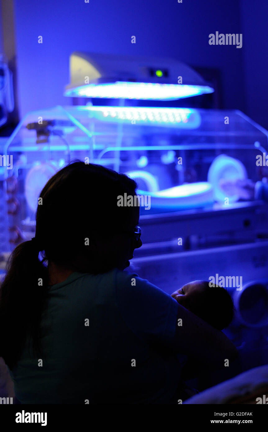 Silhouette of Mother and Newborn Child in Hospital, Incubator and Light Therapy in Background Stock Photo