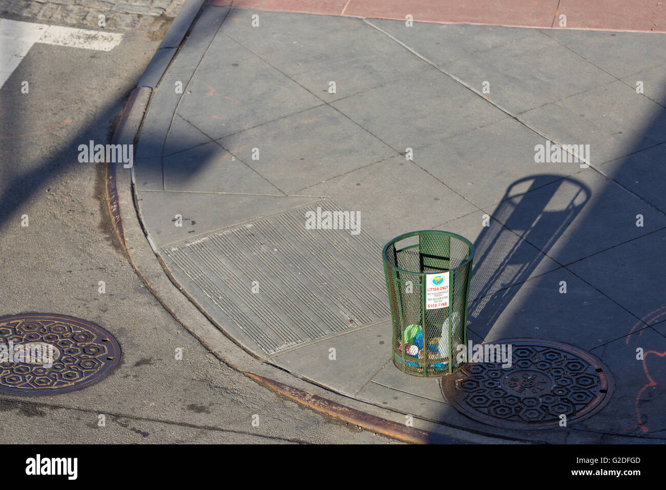 NYC street corner consisting of a manhole covers and green metal trash can in Tribeca Stock Photo