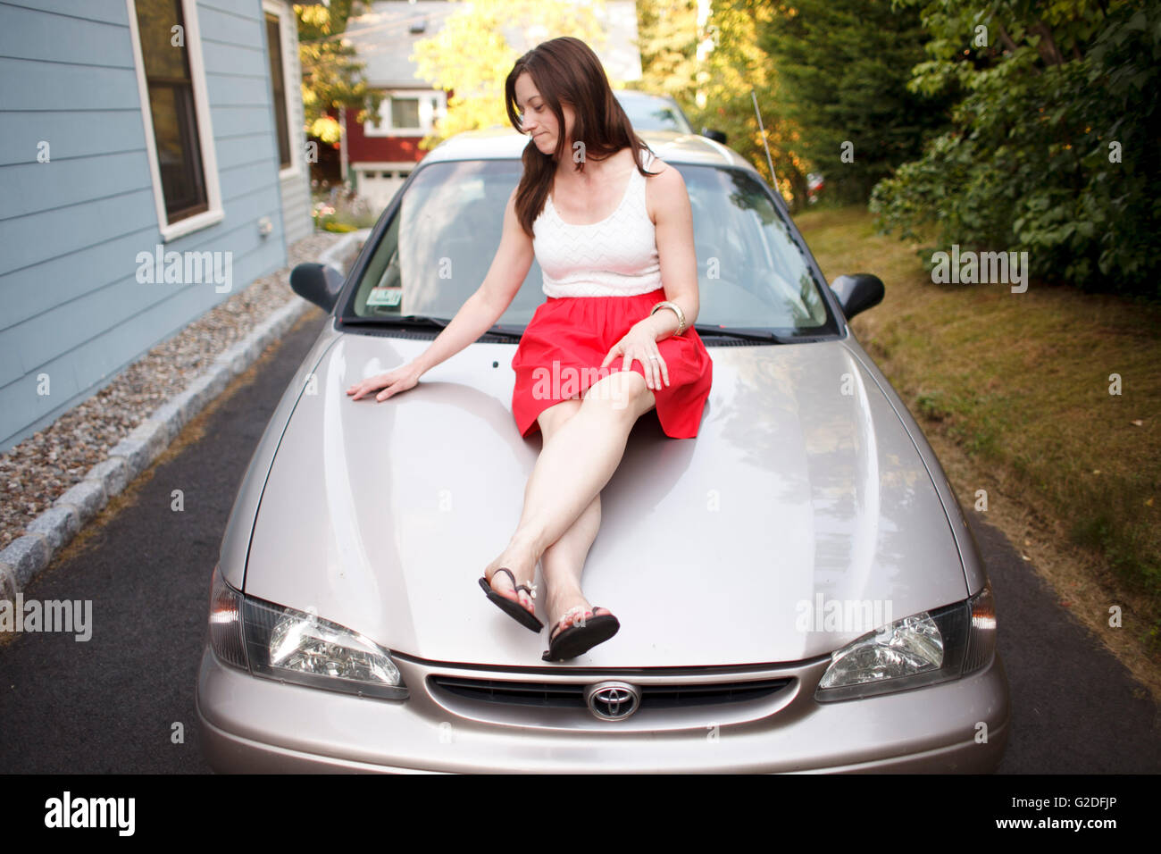 Woman Sitting on Car Hood Stock Photo