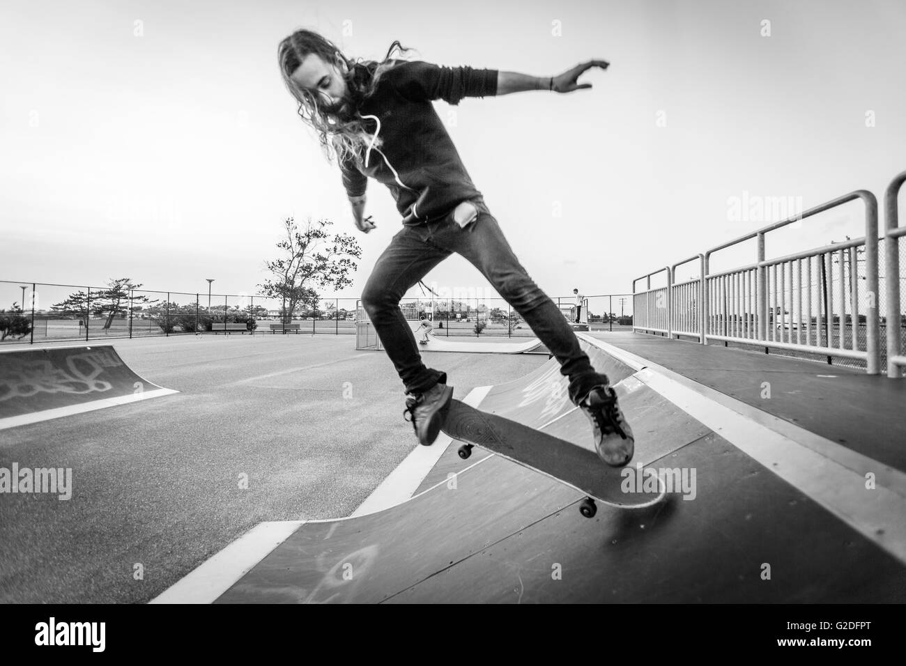 Young Adult Man Doing Tricks with Skateboard at Skate Park Stock Photo