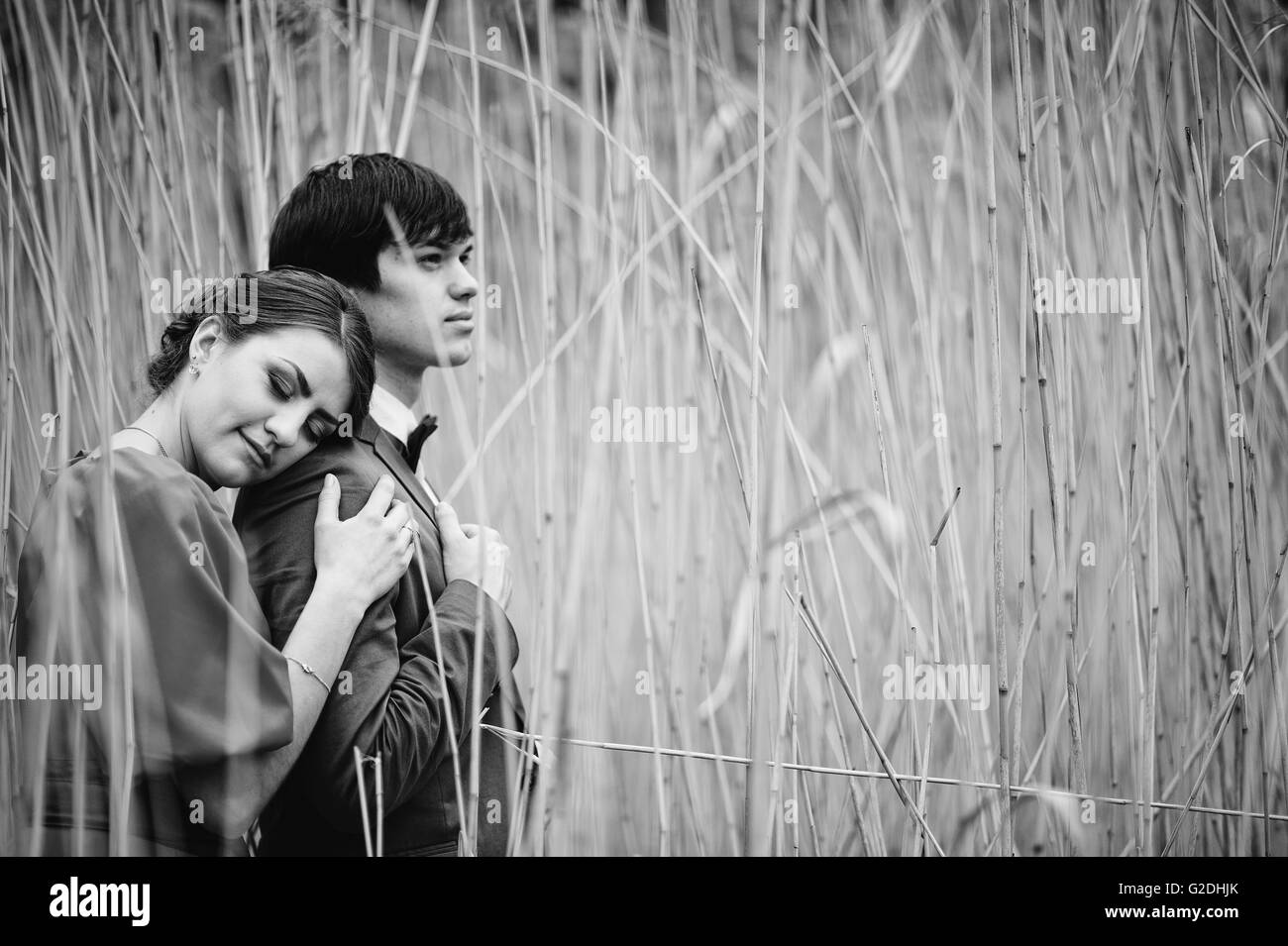 Couple hugging in love at high cane. Stylish man at velvet jacket and girl in red dress in love together. Black and white photo Stock Photo