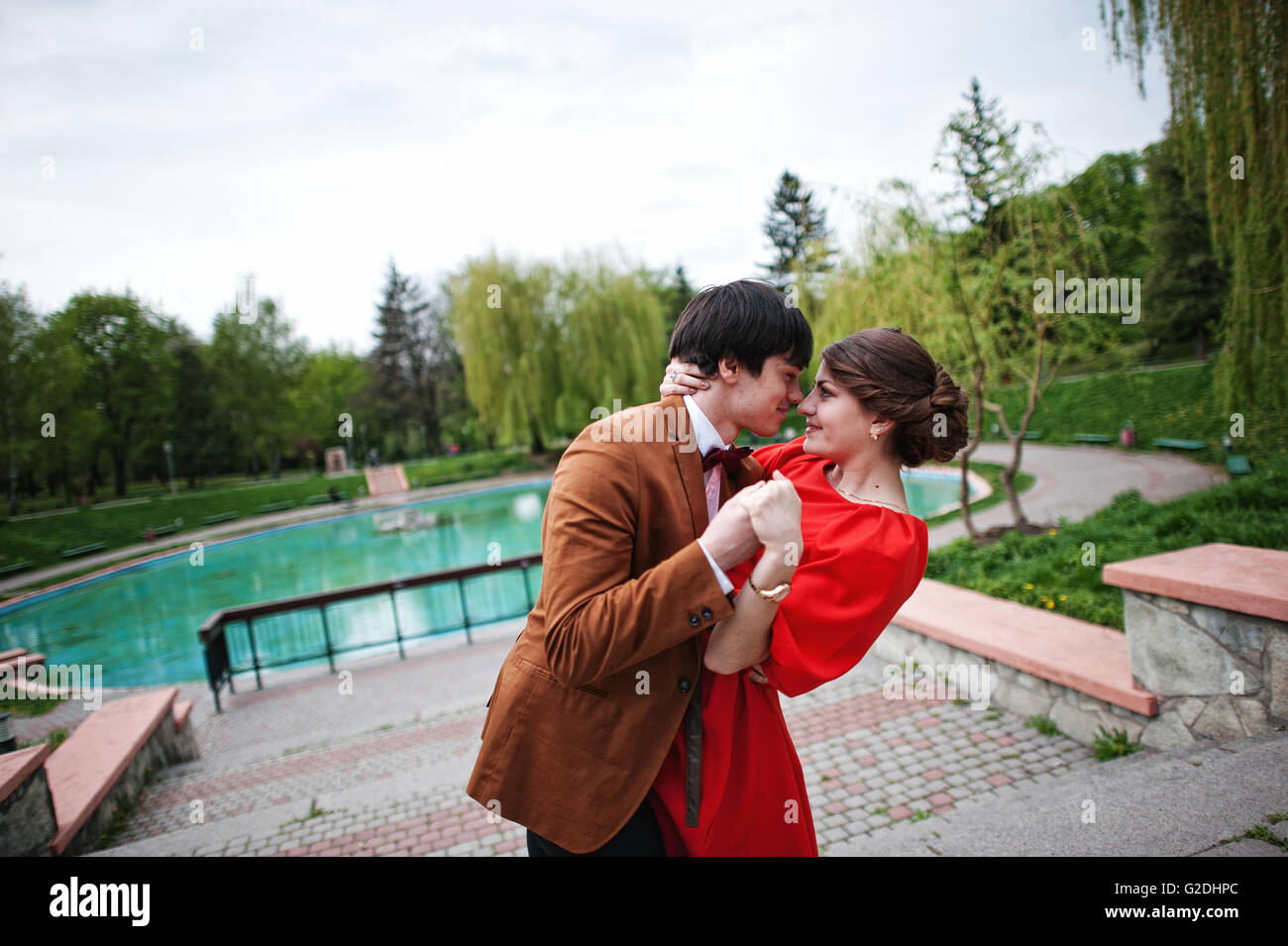 Couple hugging in love near fountain. Stylish man at velvet jacket and