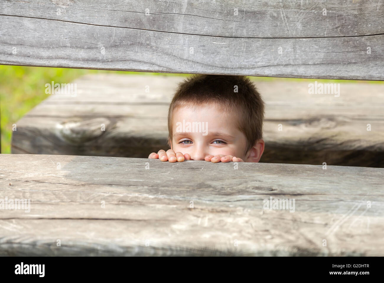 white little boy hiding under the wooden table Stock Photo Alamy