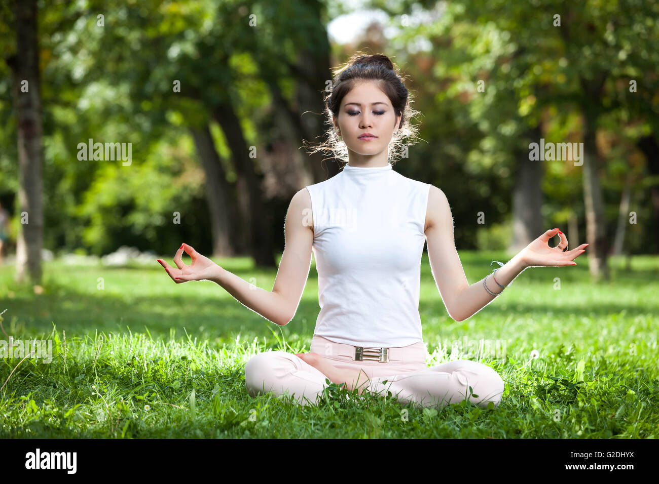 Young woman  Asian staying on a lotus position in the park doing yoga Stock Photo