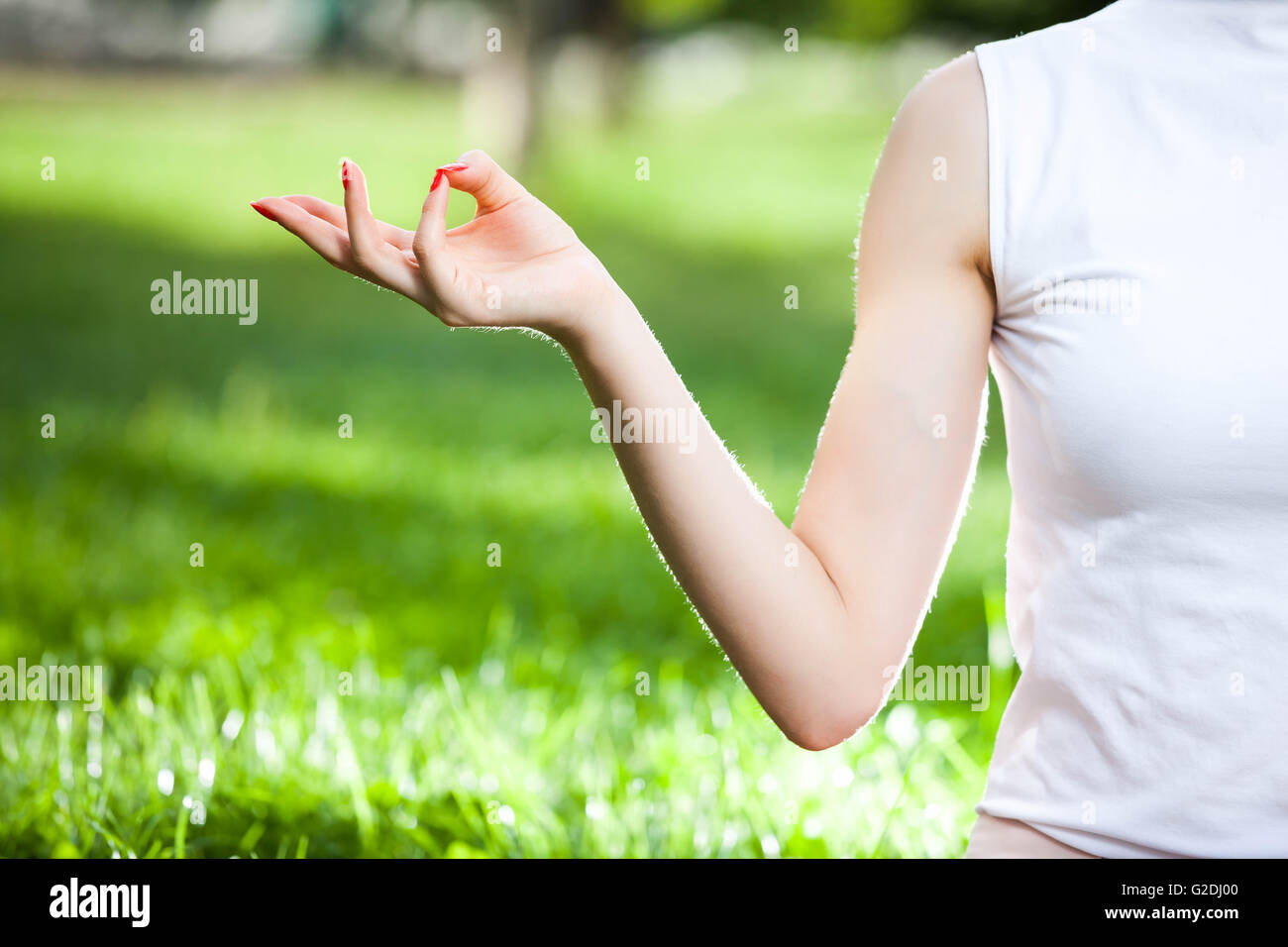 one woman Caucasian hand in yoga position symbolize water, beauty and remove impurities, on a green grass background Stock Photo