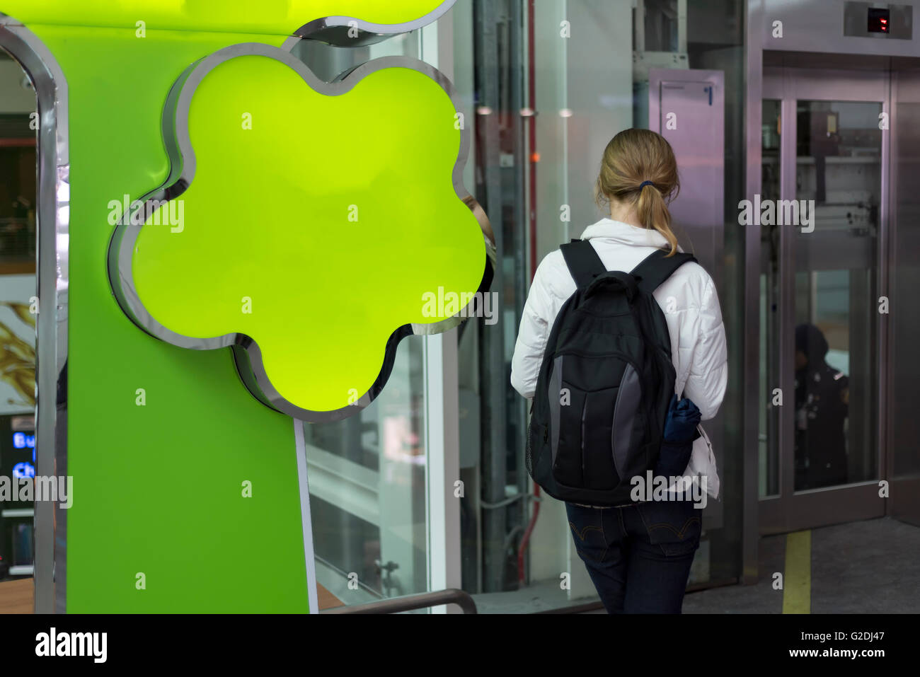 Young Caucasian  woman looking at mobile phone near elevator Stock Photo