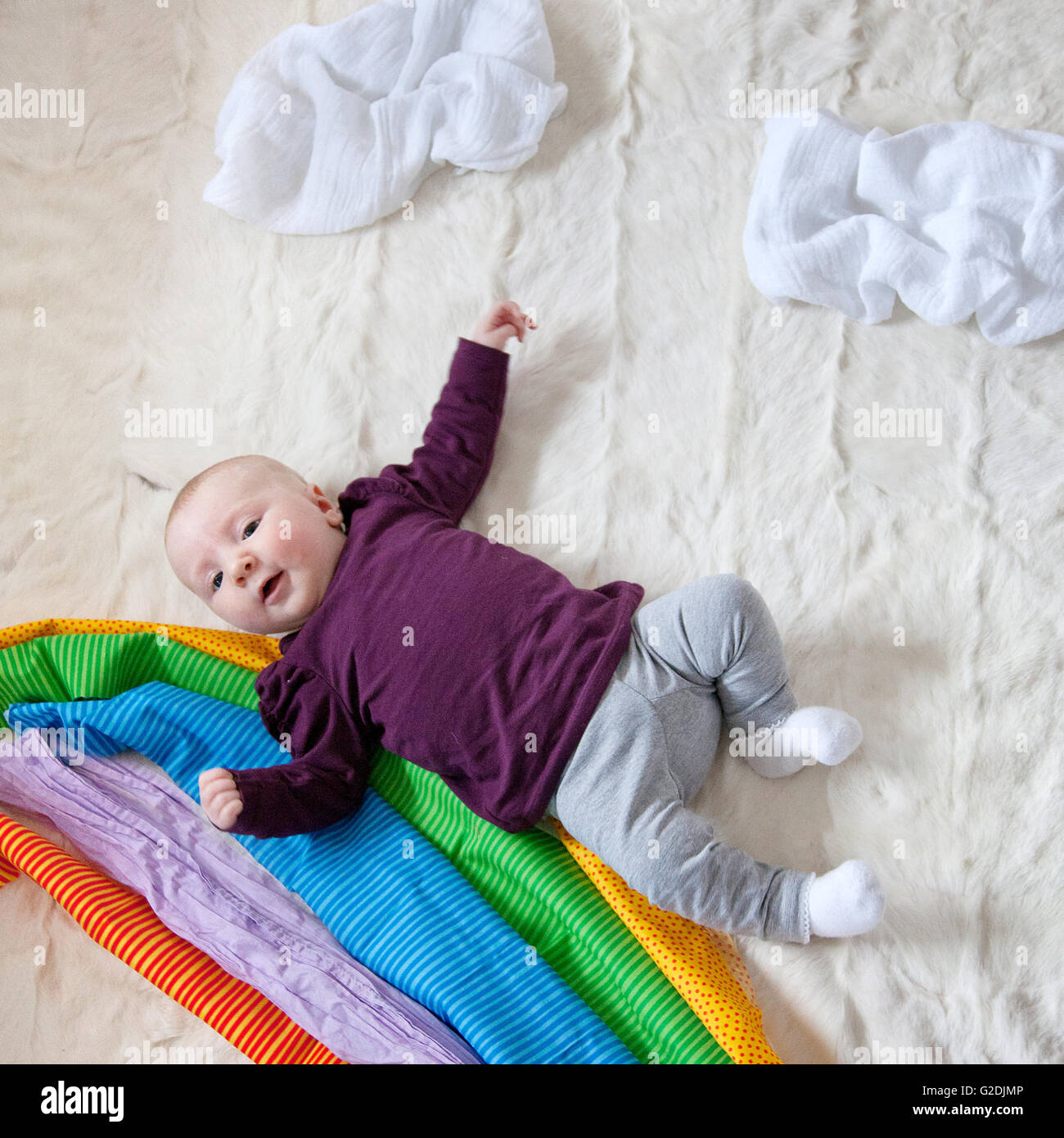 4 Month old Baby girl and colorful cloth rainbow Stock Photo
